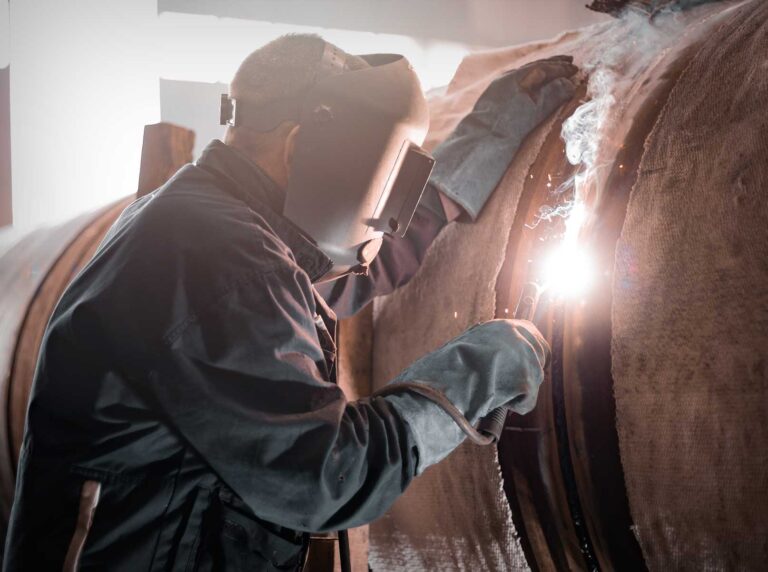 Soldador profissional totalmente equipado com EPI para soldador, como máscara de solda e vestimentas de proteção, enquanto realiza um trabalho de soldagem com segurança.