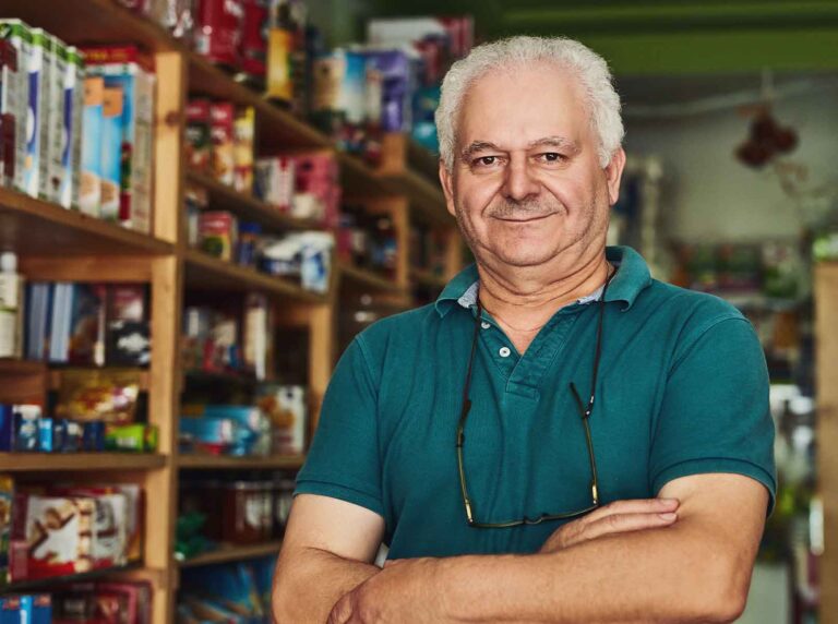 dono-de-loja-agropecuaria-um-homem-maduro-de-bracos-cruzados-em-frente-as-prateleiras-de-produtos-ilustrando-o-guia-de-como-montar-uma-loja-agropecuaria-lucrativa