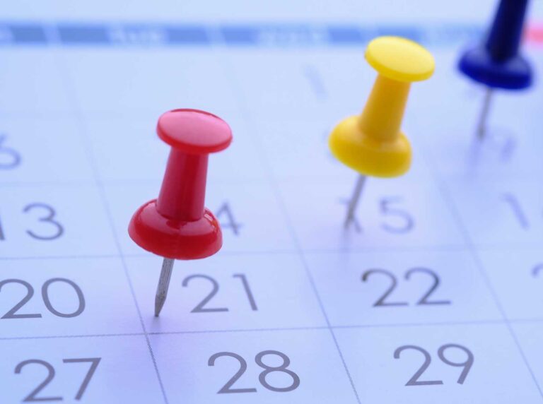 close-up-de-calendario-com-alfinetes-coloridos-marcando-datas-importantes-para-o-calendario-sst-2026-e-gestao-de-prazos