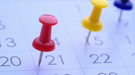 close-up-de-calendario-com-alfinetes-coloridos-marcando-datas-importantes-para-o-calendario-sst-2026-e-gestao-de-prazos