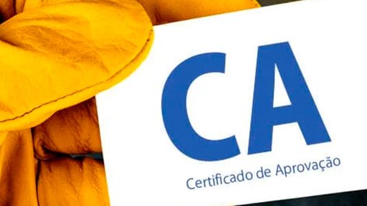 Apenas 1 luva de segurança amarela segurando um cartão com a sigla CA mais a palavra certificado de aprovação embaixo do CA.