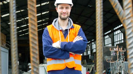 dono-de-loja-de-materiais-de-construcao-de-bracos-cruzados-usando-epi