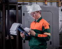 profissional-de-sst-com-capacete-e-uniforme-analisando-documentos-sobre-higiene-ocupacional-em-uma-prancheta-dentro-da-industria