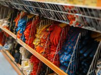 prateleira com luvas de segurança coloridas organizadas em ganchos expositores ilustrando um bom layout de loja de epi para facilitar a pega