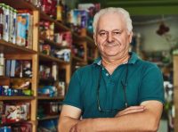 dono-de-loja-agropecuaria-um-homem-maduro-de-bracos-cruzados-em-frente-as-prateleiras-de-produtos-ilustrando-o-guia-de-como-montar-uma-loja-agropecuaria-lucrativa