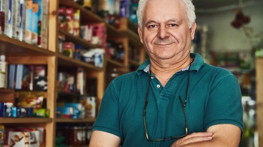 dono-de-loja-agropecuaria-um-homem-maduro-de-bracos-cruzados-em-frente-as-prateleiras-de-produtos-ilustrando-o-guia-de-como-montar-uma-loja-agropecuaria-lucrativa